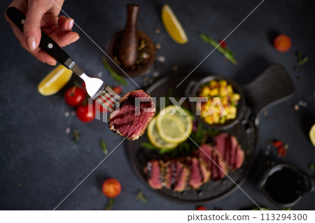Sliced Organic grilled Tuna fillet covered with sesame seeds and mango salsa on black ceramic serving board 113294300