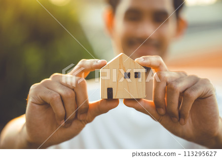 people hand holding miniature wooden house model for banking housing mortgage real estate rent lease home family concept 113295627