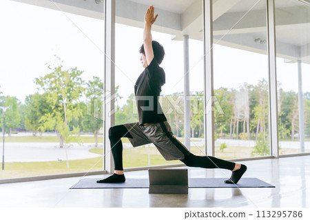 Young Asian man doing online yoga while watching videos on tablet (crescent moon pose) Young Asian man doing online yoga while watching videos on tablet (crescent moon pose) 113295786