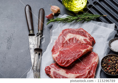 Raw ribeye steaks with savory spices Raw ribeye steaks with savory spices 113296789