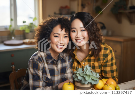 Joyful Asian mother and teenage daughter hugging in a cozy kitchen looking at the camera 113297457