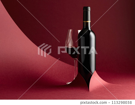 Bottle and glass of red wine on a red background. 113298038