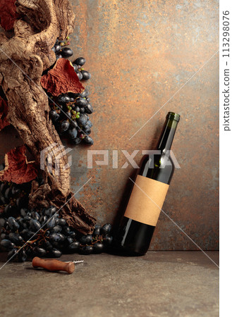 Bottle of red wine with blue grapes on a rusty background. Bottle of red wine with blue grapes on a rusty background. 113298076