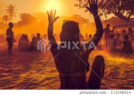 A young woman with her arms raised in the air enjoys the Indian festival of Holi at sunset 113298414