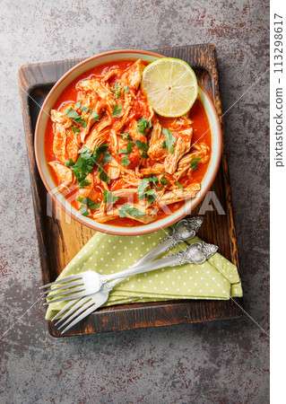 Crock pot chicken tomato salsa with taco seasoning and lime close-up in a bowl on a wooden board. Vertical top view 113298617