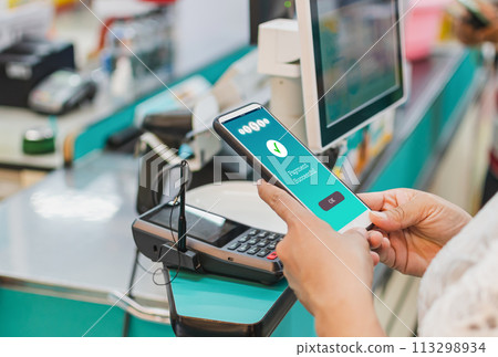 woman hand holds a smartphone on screen with message Payment Successful in a supermarket. Concept of financial transactions with mobile devices. Closeup, money, transfer, online. blurred background woman hand holds a smartphone on screen with message Payment Successful in a supermarket. Concept of financial transactions with mobile devices. Closeup, money, transfer, online. blurred background 113298934