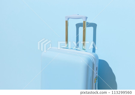 Suitcase on a pastel blue background with long deep shadows. Minimal style 113299560
