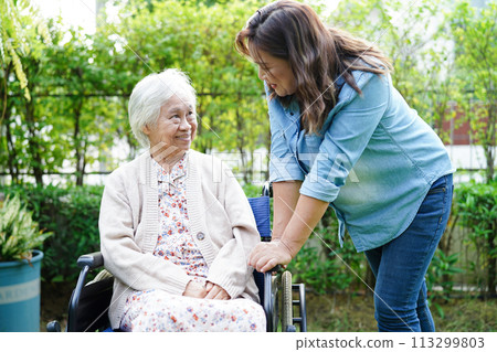 Caregiver help Asian elderly woman disability patient sitting on wheelchair in park, medical concept. 113299803