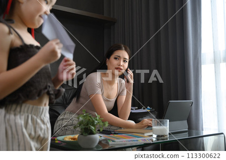 Unhappy freelancer mother trying to working at home while her daughter romping around 113300622