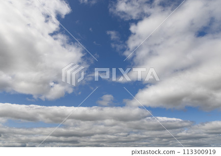 Layers of voluminous clouds against a vivid blue backdrop, ideal for design aesthetics Layers of voluminous clouds against a vivid blue backdrop, ideal for design aesthetics 113300919