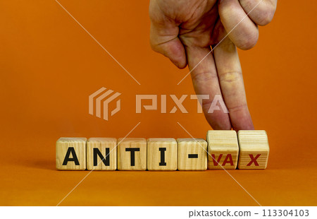 Anti-vax symbol. Doctor turns cubes with words 'anti-vax'. Beautiful orange background. Copy space. Business, medical covid-19 vaccination or anti-vax concept. Anti-vax symbol. Doctor turns cubes with words 'anti-vax'. Beautiful orange background. Copy space. Business, medical covid-19 vaccination or anti-vax concept. 113304103