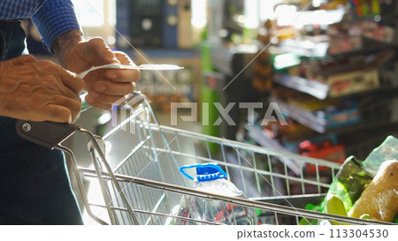 A grocery check in the hands of an elderly man A grocery check in the hands of an elderly man 113304530