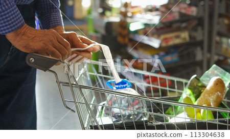 A grocery check in the hands of an elderly man 113304638