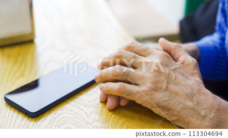 Hands of an elderly male cafe customer at a table waiting 113304694