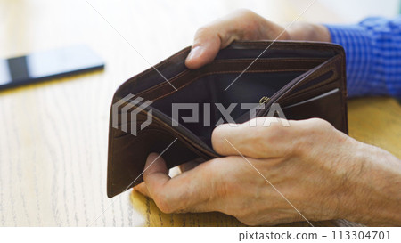 An empty wallet with no money in the hand of an elderly white man about to place an order at a cafe 113304701