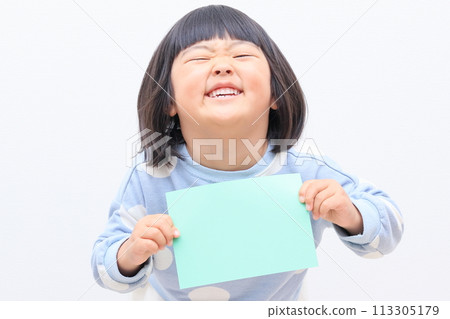 3 year old girl holding a piece of paper for copy space 113305179