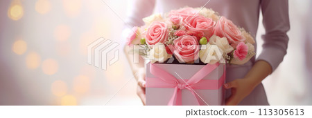 Close up of gift box with pink bouquet on gift box in female hands. Banner or gift card for Happy Mother's Day or Happy Women's day, birthday. Close up of gift box with pink bouquet on gift box in female hands. Banner or gift card for Happy Mother's Day or Happy Women's day, birthday. 113305613