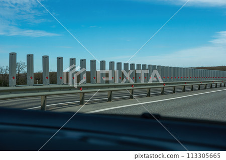 A road with a long line of metal posts with red hearts on them. The road is empty and the sky is clear. A road with a long line of metal posts with red hearts on them. The road is empty and the sky is clear. 113305665