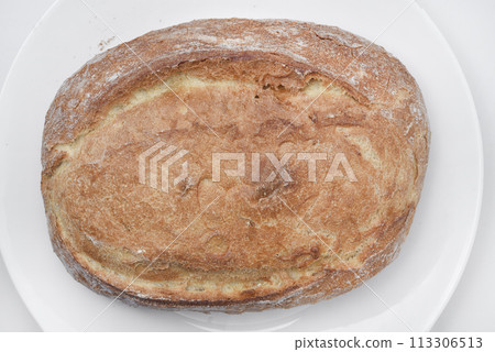 A fresh loaf of bread on a plate. A piece of delicious bread. Bakery products. A fresh loaf of bread on a plate. A piece of delicious bread. Bakery products. 113306513