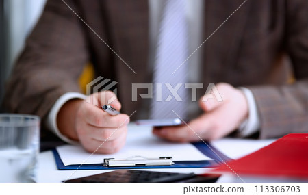 Male arm in suit hold phone and silver pen 113306703