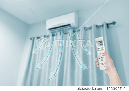 woman holding air conditioner remote control with air conditione 113306741
