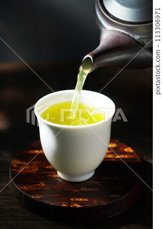 Green tea poured from a teapot 113306971