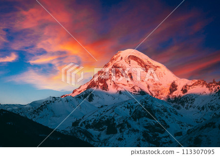 Georgia. Mount Kazbek Covered Snow In Winter Sunrise. Morning Dawn Colored Top Of Mountain In Pink-orange Colors. Awesome Winter Georgian Nature Landscape. 113307095