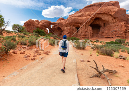 Woman Hiking to Double Arch in Utah National Park 113307569