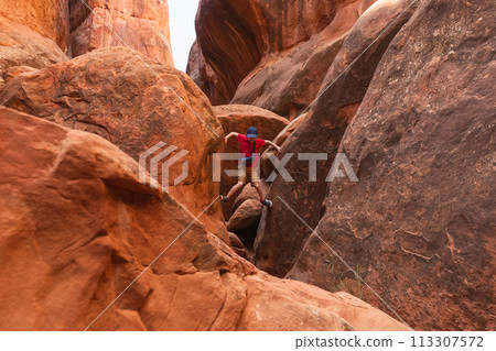 Boy Climbing Rocks in Arches National Park, Utah 113307572