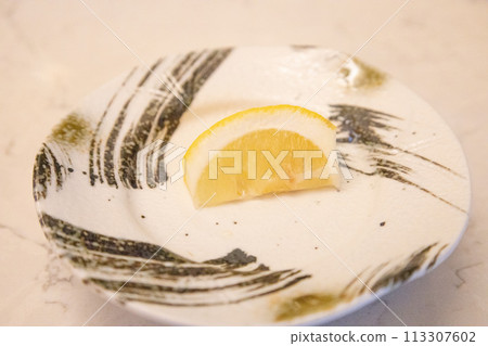 Comb-shaped cut lemons on a Japanese-style/patterned plate, lemons served as a side dish on the dining table (Tokyo) 113307602