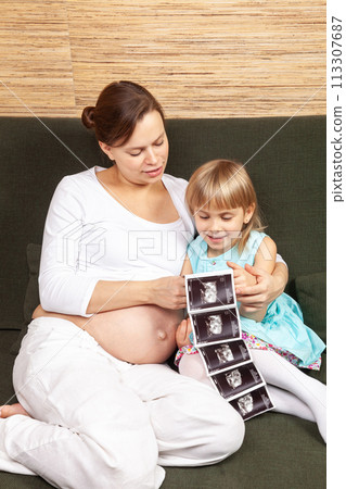Expectant Mother and Daughter Looking at Ultrasound Expectant Mother and Daughter Looking at Ultrasound 113307687