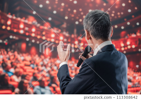 Man speaking in front of a large audience 113308642