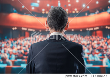 Man speaking in front of a large audience 113308644
