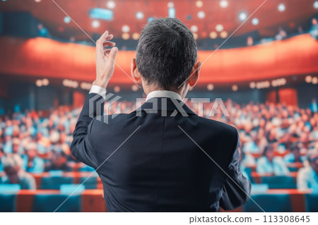 Man speaking in front of a large audience 113308645