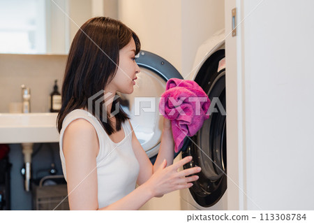 A young woman using a drum washing machine A young woman using a drum washing machine 113308784
