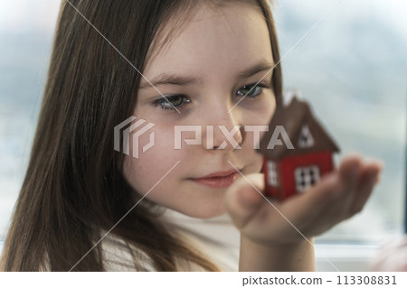 Little teenage girl looking at a model of a house. He dreams of his own home. Selected Focus. High quality photo Little teenage girl looking at a model of a house. He dreams of his own home. Selected Focus. High quality photo 113308831