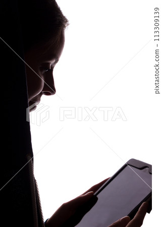 Silhouette of a girl in the hood with a tablet 113309139