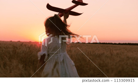 Happy little girl kid in white dress running with plane toy on wheat field at sunset sunrise horizon back view closeup. Adorable female child playing aircraft imagine pilot flying at dusk dawn meadow Happy little girl kid in white dress running with plane toy on wheat field at sunset sunrise horizon back view closeup. Adorable female child playing aircraft imagine pilot flying at dusk dawn meadow 113309915