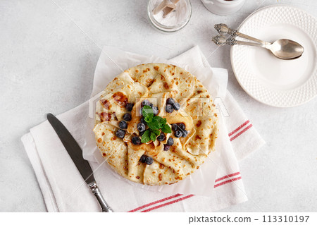 Crepe cake with custard vanilla cream and berries and mint leaves. top view 113310197