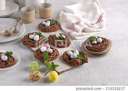 Easter chocolate cookies in the shape of Nests with sweet eggs on light table with mint leaves 113310217