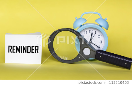There is a clock and a magnifying glass on a yellow background, with the inscription REMINDER There is a clock and a magnifying glass on a yellow background, with the inscription REMINDER 113310403