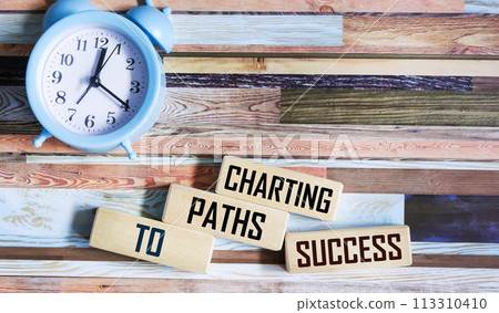 Charting paths to success quotes on wooden blocks and vintage background with clock 113310410