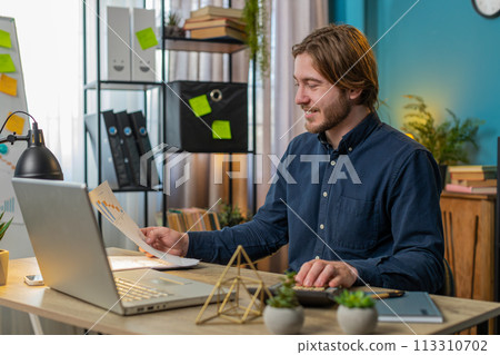 Focused office worker man working with schedules financial graphics while using calculator laptop 113310702