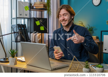 Smiling businessman using smartphone application online pointing showing like remote distance job Smiling businessman using smartphone application online pointing showing like remote distance job 113310706