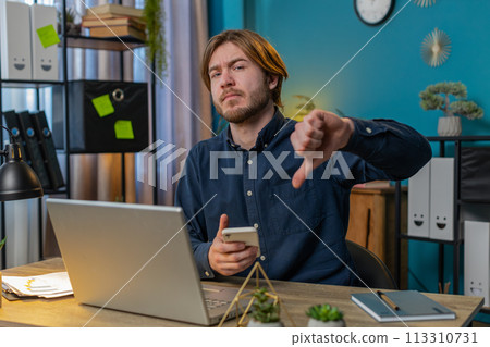 businessman using smartphone at home office showing thumbs down sign gesture dislike disapproval 113310731