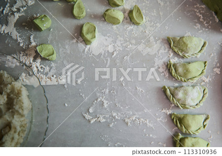 Top view. Food background with molded raw dumplings, Ukrainian Varennyky and Italian ravioli on a floured marble surface of kitchen table. Traditional cuisine. Food background. Copy advertising space Top view. Food background with molded raw dumplings, Ukrainian Varennyky and Italian ravioli on a floured marble surface of kitchen table. Traditional cuisine. Food background. Copy advertising space 113310936