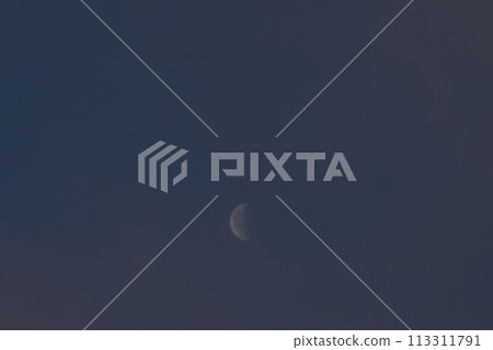 A waning crescent moon at 23.2 days old lingers between the clouds in the dawn sky. 113311791