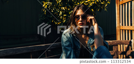 Stylish woman sitting on a bench in sunlight 113312534