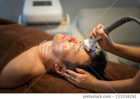 A man receiving facial treatment using cavitation at a men's beauty salon (skin care) A man receiving facial treatment using cavitation at a men's beauty salon (skin care) 113316291