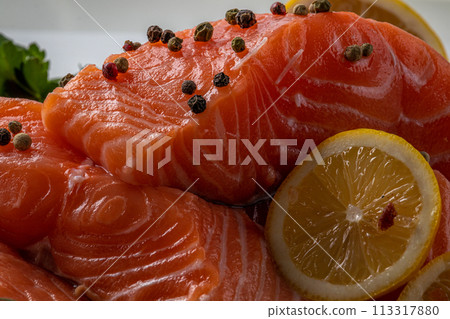 Fresh raw salmon fillet with cooking ingredients, herbs and lemon on black slate Fresh raw salmon fillet with cooking ingredients, herbs and lemon on black slate 113317880
